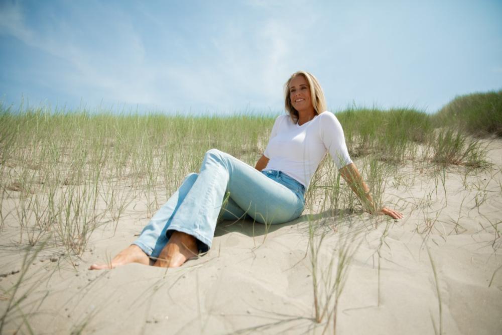 Vrouw zit in de duinen aan het strand